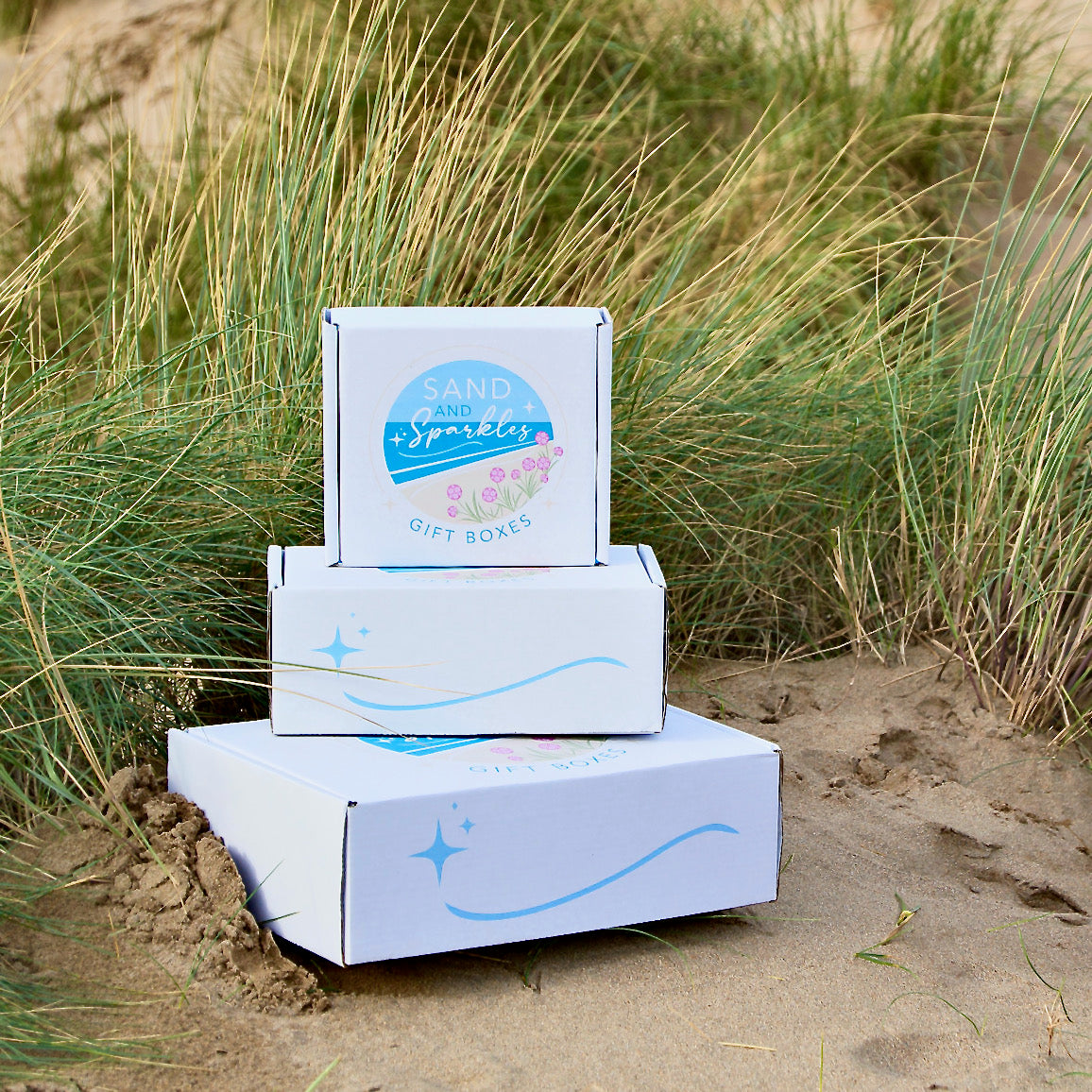 Sand and Sparkle Gift Boxes stacked in the sand in Devon