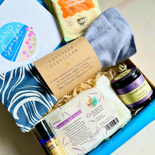 Wellbeing Gift Set with Devon and Cornish products including organic lavender eye pillow, bath bombs, hand cream, sleep oil and herbal tea in Sand and Sparkle Gift Box